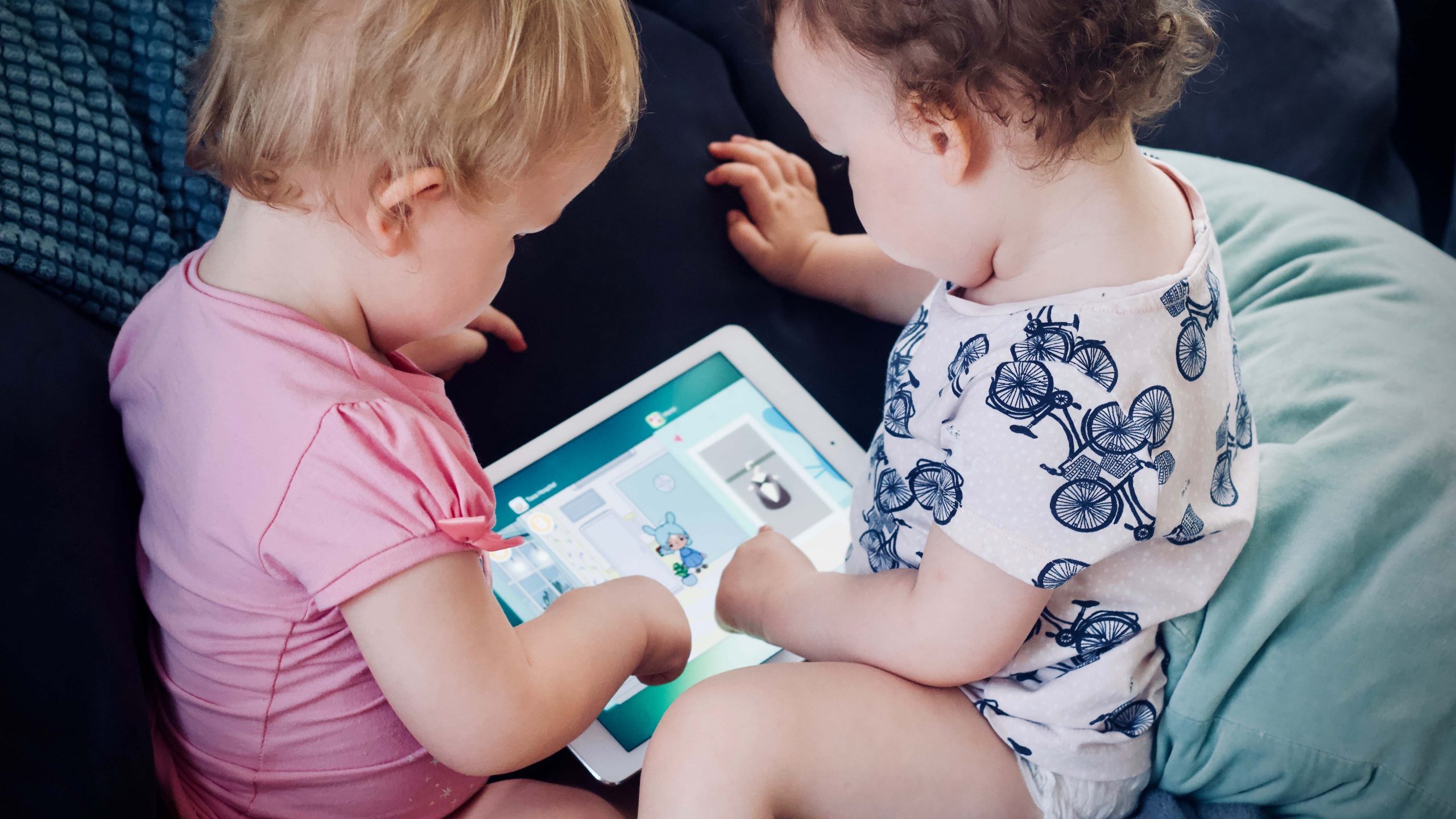 two little kids plyaing together with an ipad
